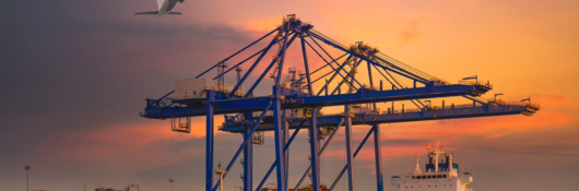 Cargo ship at a port with cargo containers with airplane overhead